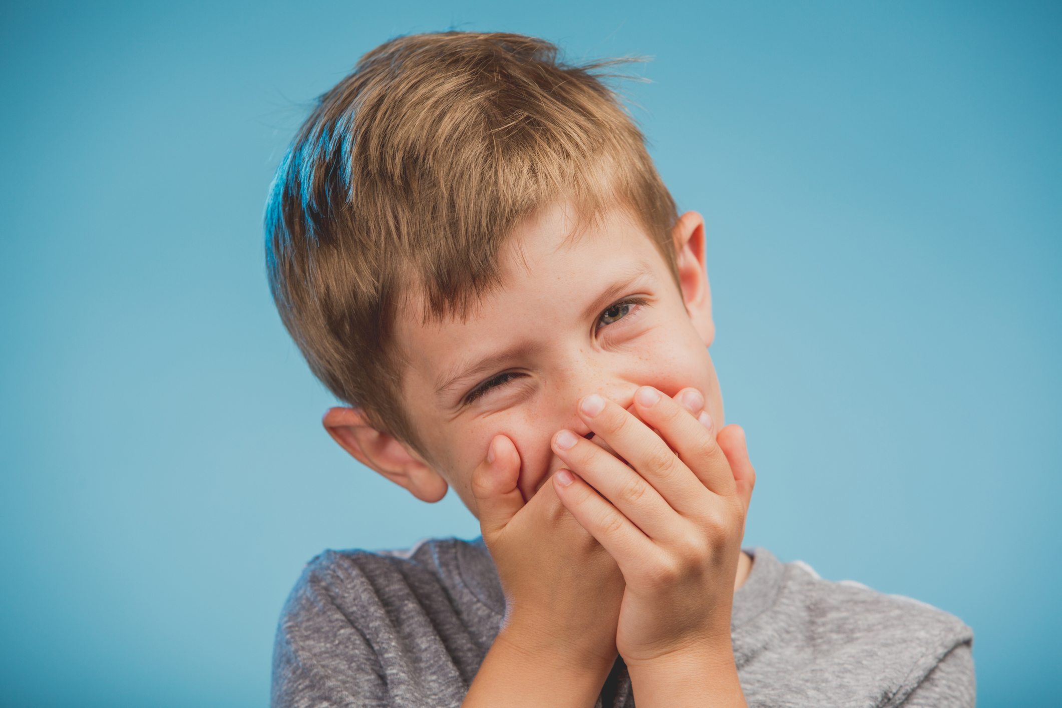 Young boy with his hands over his mouth