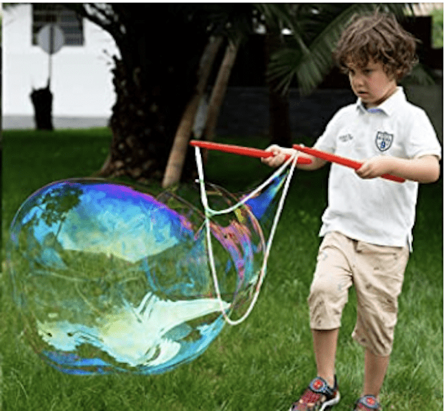 A boy playing with a giant bubble kit outside