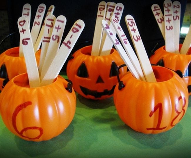 Small plastic pumpkins labeled with numbers filled with craft sticks with math problems written on them