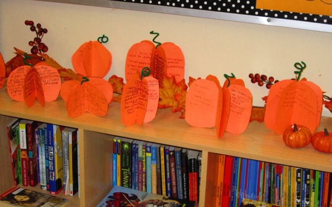 3-D paper pumpkins with stories written on them laid out on a bookshelf