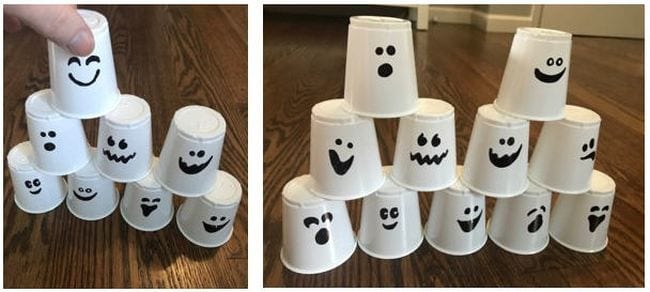 Student stacking white paper cups with ghost faces drawn on them (Halloween activities)