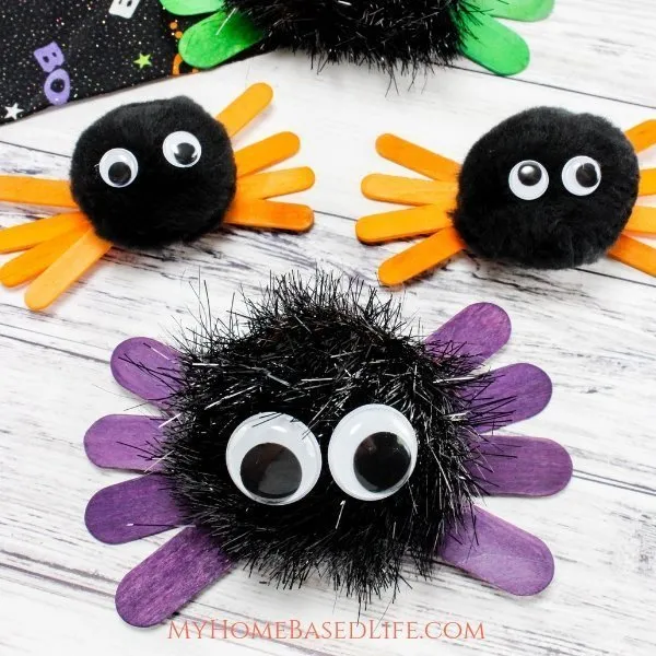 Fall art projects can include spiders like these ones made from black pom poms with popsicle stick legs and googly eyes.