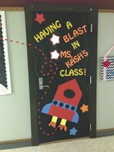 Black classroom door decorated with stars and a space ship