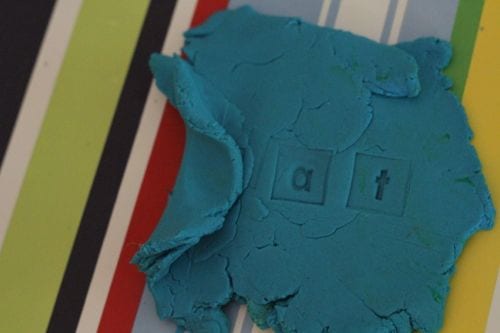 A flattened ball of blue play dough on a striped background