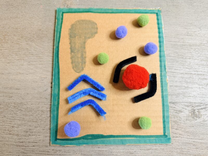 a cardboard plant cell model made out of cardboard, pom poms and pipe cleaners