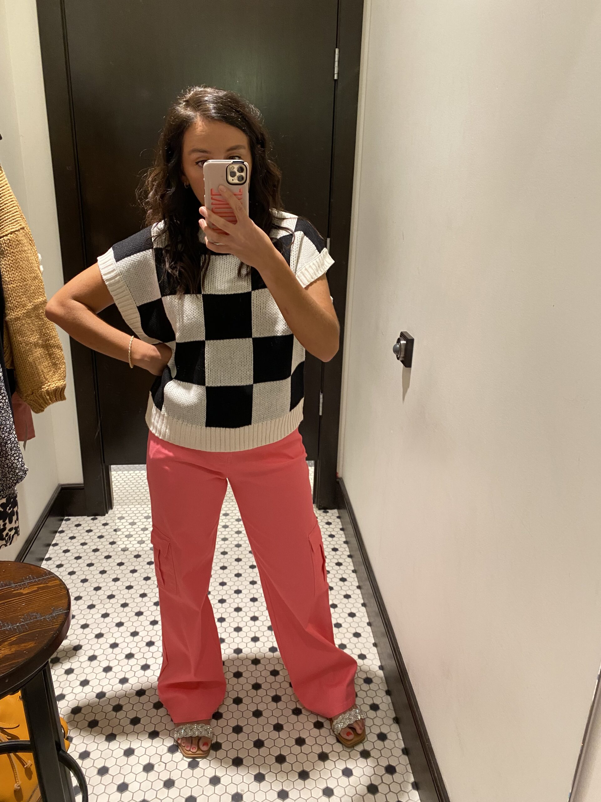 Woman in mirror wearing a checkered shirt and pink pants as an example of cute teacher outfits