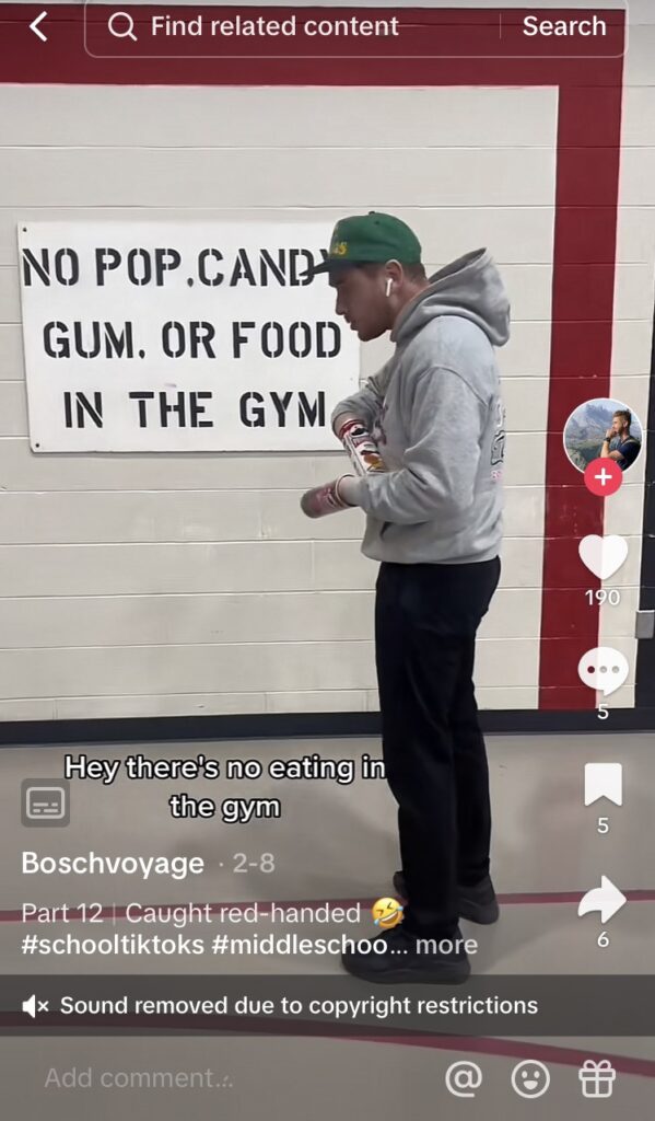 Middle school student is eating chips, drinking pop, and chewing gum in front of a sign that says not to.