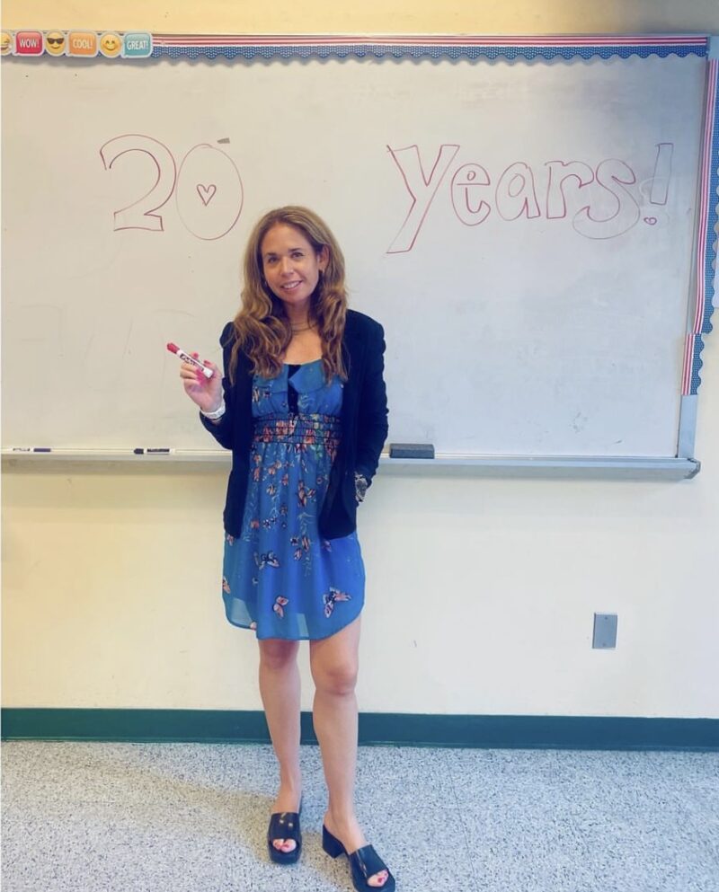 Sari Beth Rosenberg stands in front of her white board, which reads "20 Years"