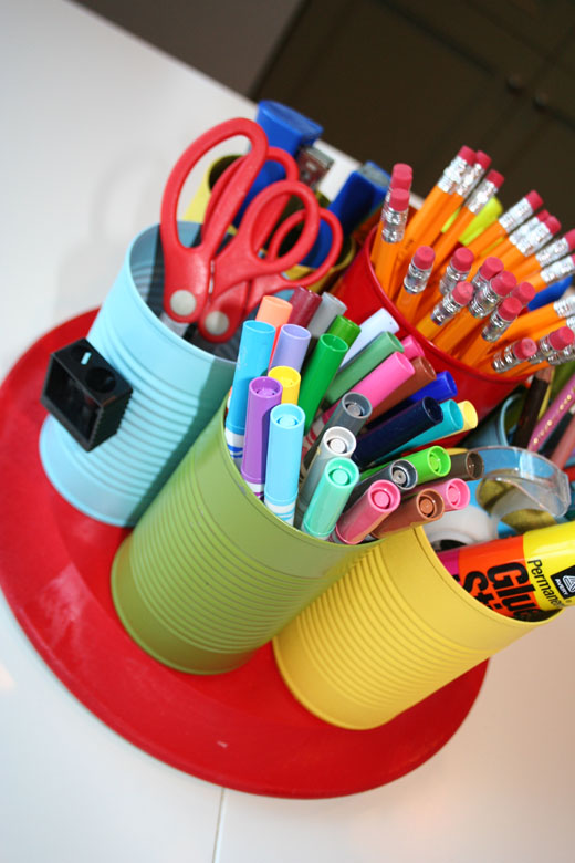 Old cans are painted green, blue, and yellow and are used as holders for scissors, pencils, markers, etc.