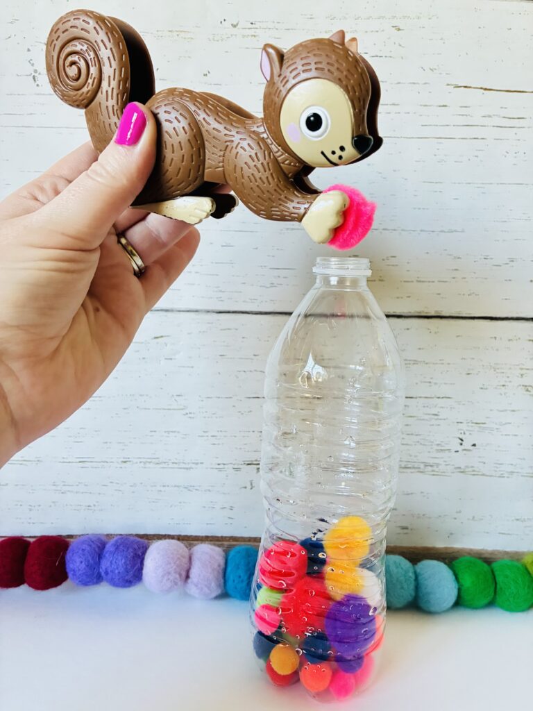 an image of a fine motor activity that has students use toy tweezers and put pom-poms into a water bottle