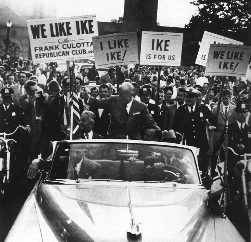 A photo of Dwight Eisenhower riding through a crowd in a convertible
