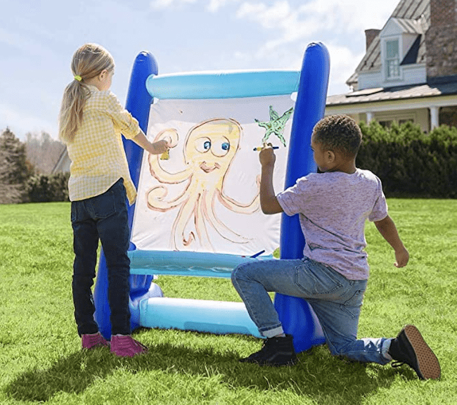 Two children outside painting on an inflatable easel, as an example of educational outdoor toys