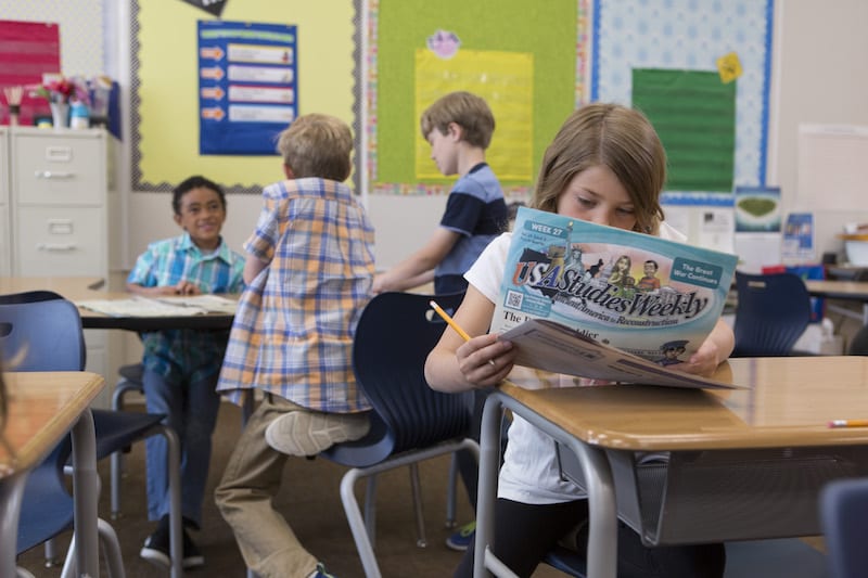 Student in classroom reading newspaper