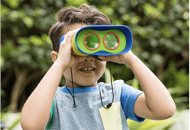 Boy outside using kidnoculars to explore, as an example of educational outdoor toys