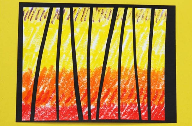 Red, orange, and yellow crayon design cut into pieces and glued on black paper