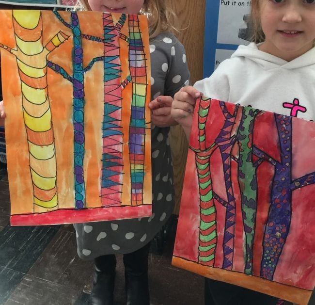 Children holding paintings of tree trunks, divided into sections with different colors and textures in each