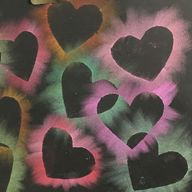 Black construction paper with heart shapes outlined by chalk pastels