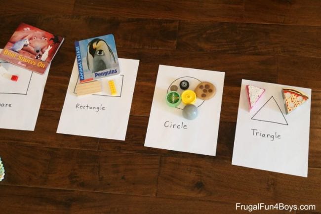 Papers labeled rectangle, circle, and triangle with various objects matching the shapes on each