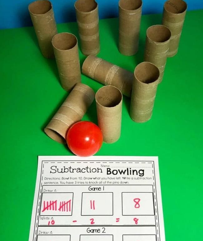 Toilet paper tubes set up like bowling pins, with a red ball and worksheet called Subtraction Bowling