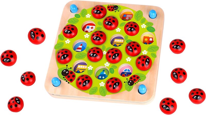 A wooden board has little circular holes in it some of which are filled with lady bug circles.