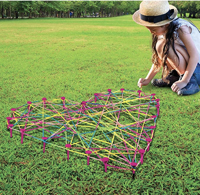 Girl creating lawn string art in her backyard, as an example of educational outdoor toys