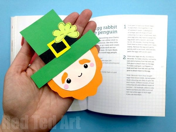 Hand holding a leprechaun bookmark over an open book for a st patrick's day activity 