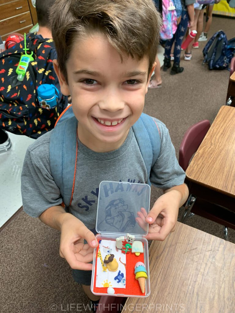 A smiling young boy showing off his desk pet and accessories