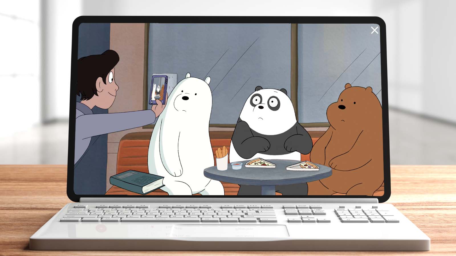 Photo of a laptop on a table with a screenshot of a We Bare Bears episode