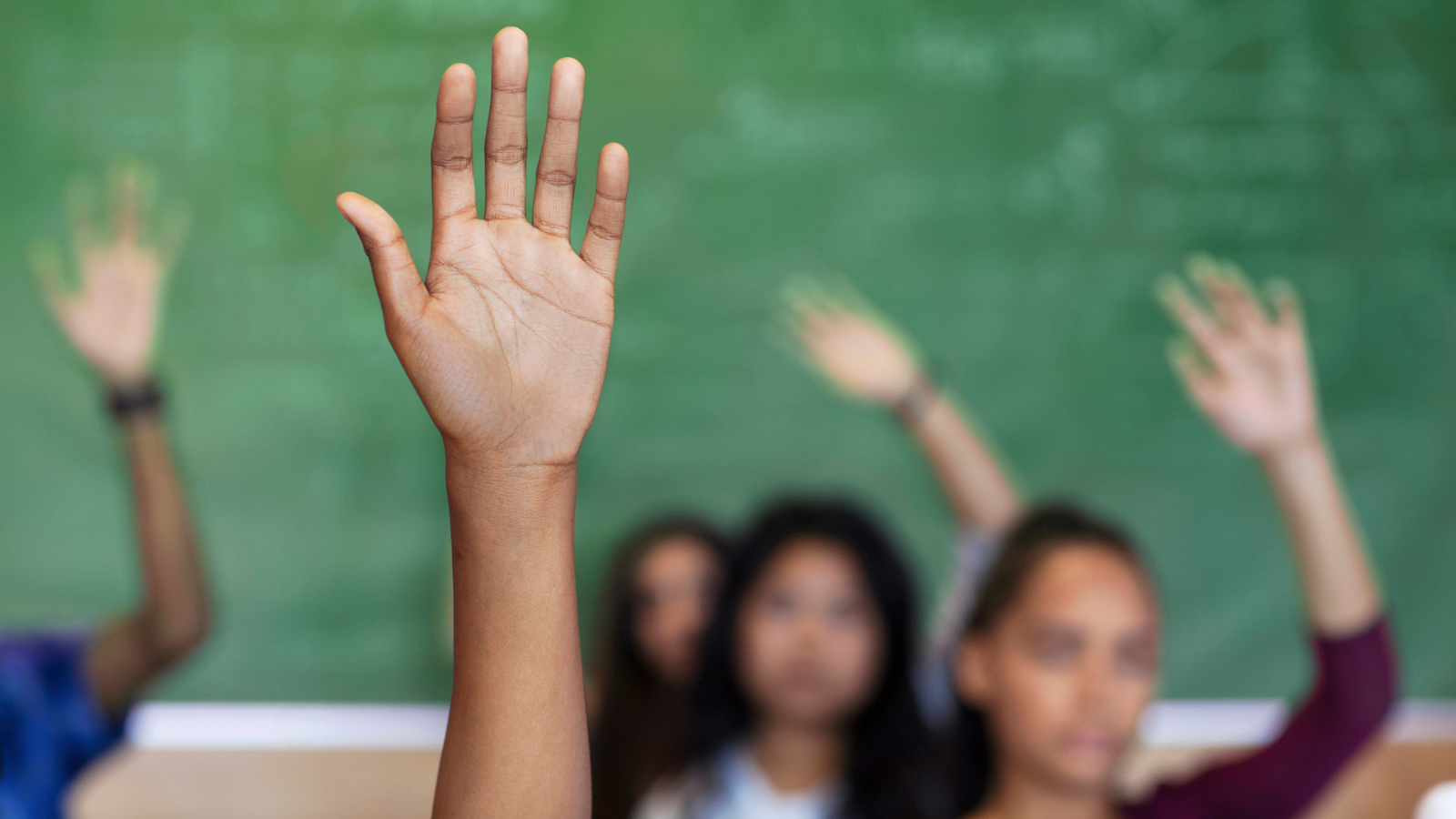 migrant students raising hands in class
