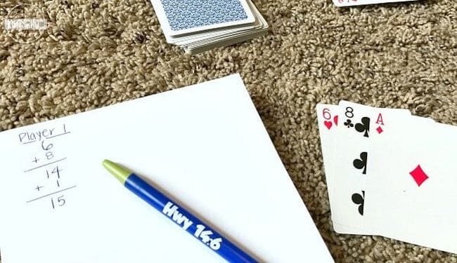 Playing cards with pen and paper on which is written a running total for Player 1