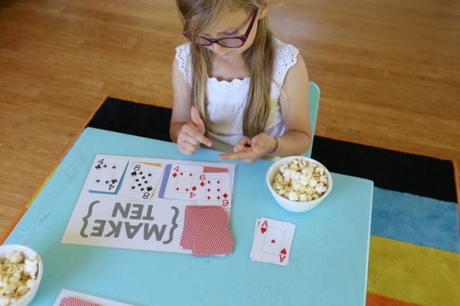 Student using playing cards and free printable worksheet to play Make Ten