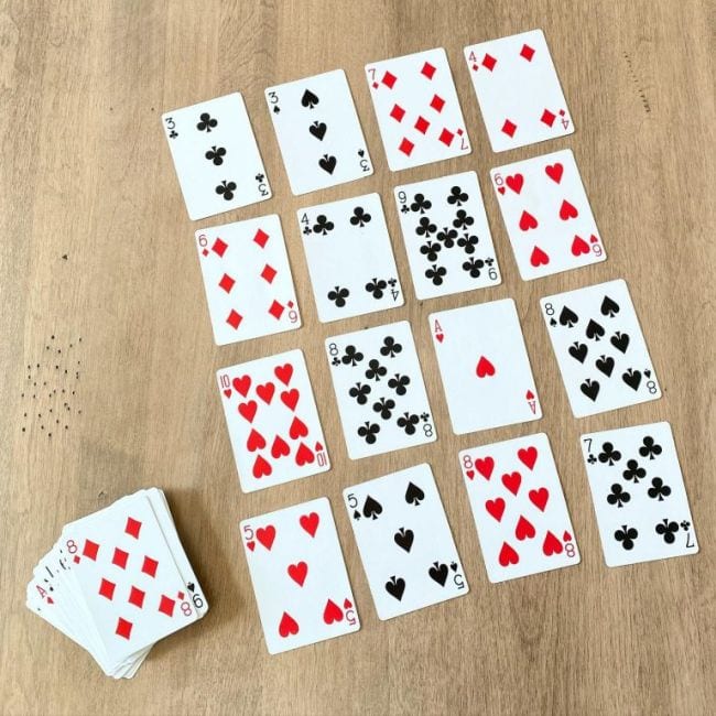 Playing cards laid out face up in four rows of four, with a deck next to it (Math Card Games)