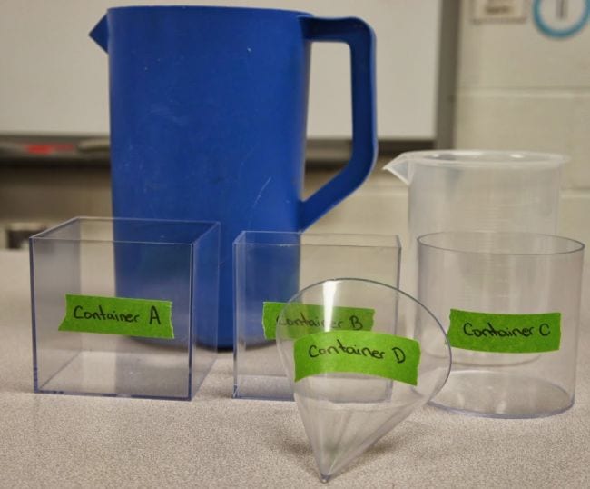 A blue pitcher and four clear containers of different measurement sit on a counter