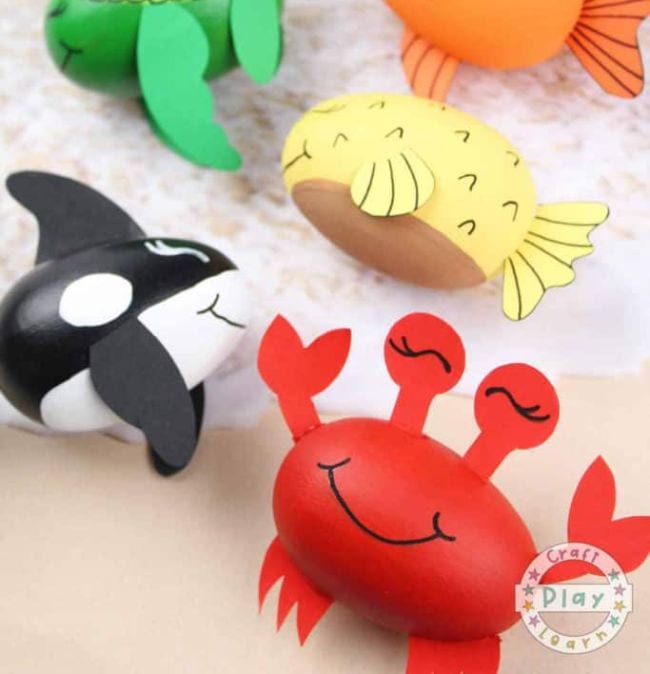 Wooden eggs are painted to look like various sea creatures include a fish, a crab, a whale, and a turtle (ocean activities)