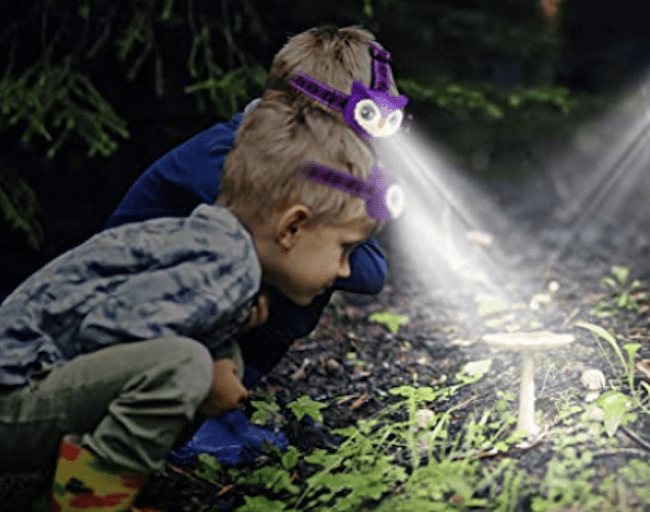 Two boys wearing headlamps and exploring outside at night, as an example of educational outdoor toys