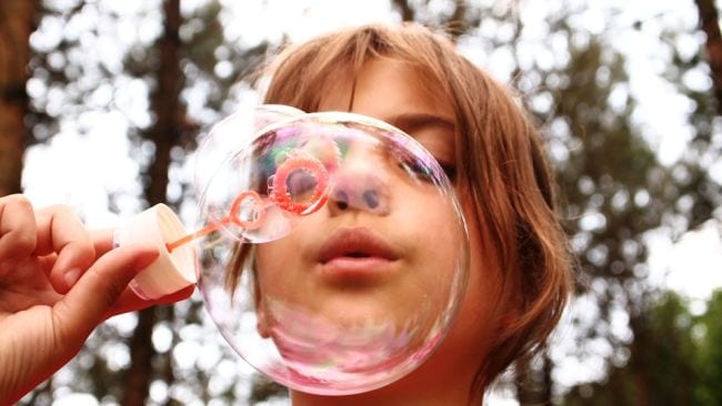 Student blowing a soap bubble through a bubble wand