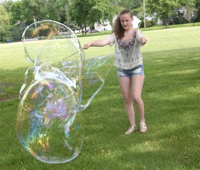 Girl making an enormous bubble with string and wire (Easy Science Experiments)