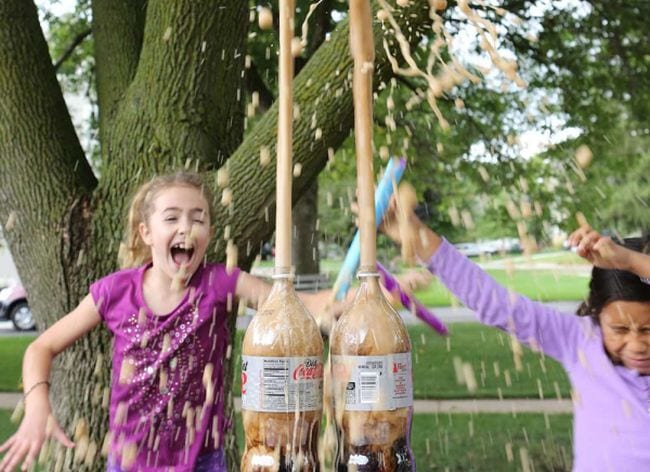 Students looking surprised as foamy liquid shoots up out of diet soda bottles