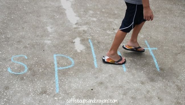 Student walking along the letters of the word SPLIT spelled out with sidewalk chalk
