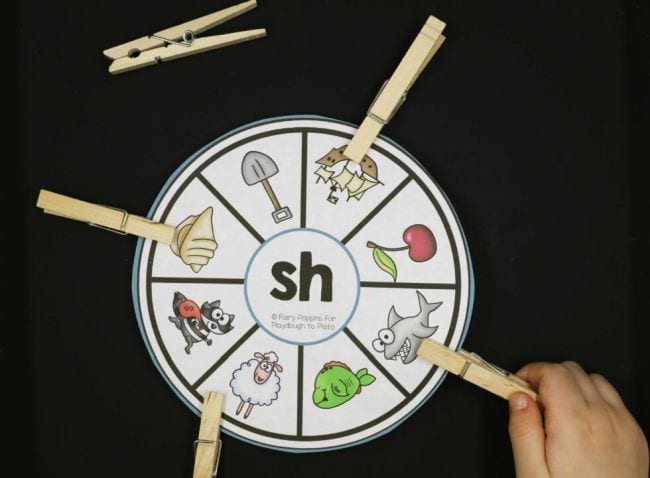 Child using clothespins to mark words that include the "sh" sound on a diagraph clip wheel