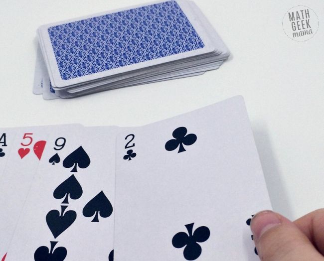 Pile of playing cards with four cards overturned on a table for pi day activities for the classroom Pi Day Activities