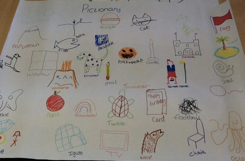 paper covered with drawings that students have done as part of a pictionary game. drawings including a pumpkin for halloween and a turtle. 