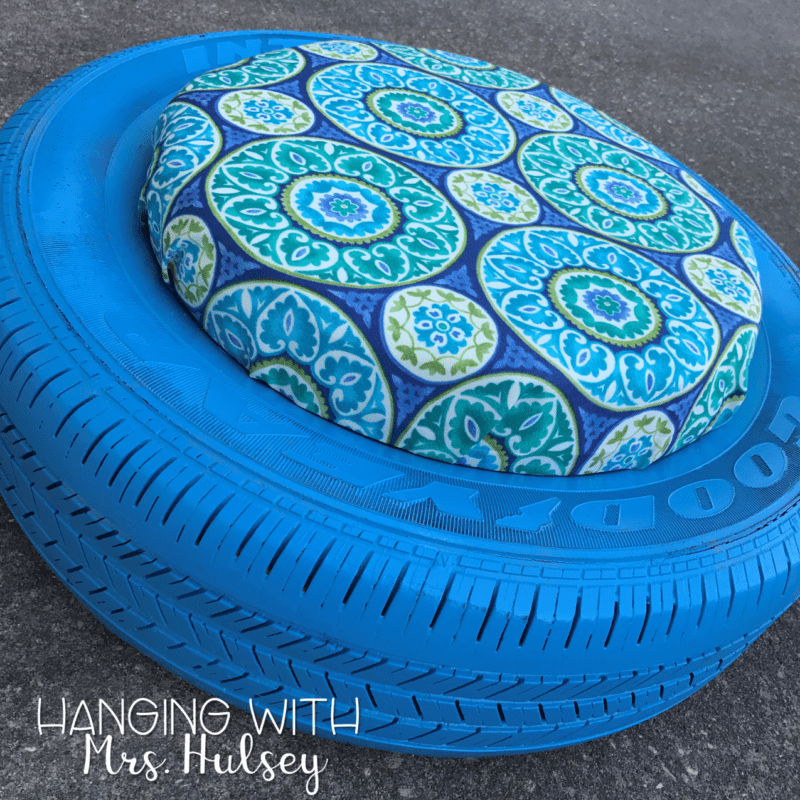 A tire is spray painted blue. A patterned fabric covers the cushion in the middle. 