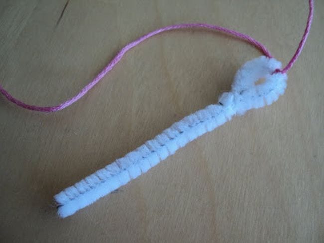 A white pipe cleaner has a thread strung through it.