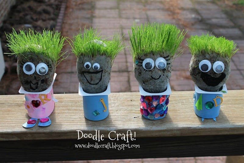 creatures made from yogurt containers with clumps of dirt sticking out of the top, with grass hair, googly eyes and smiles drawn with a marker