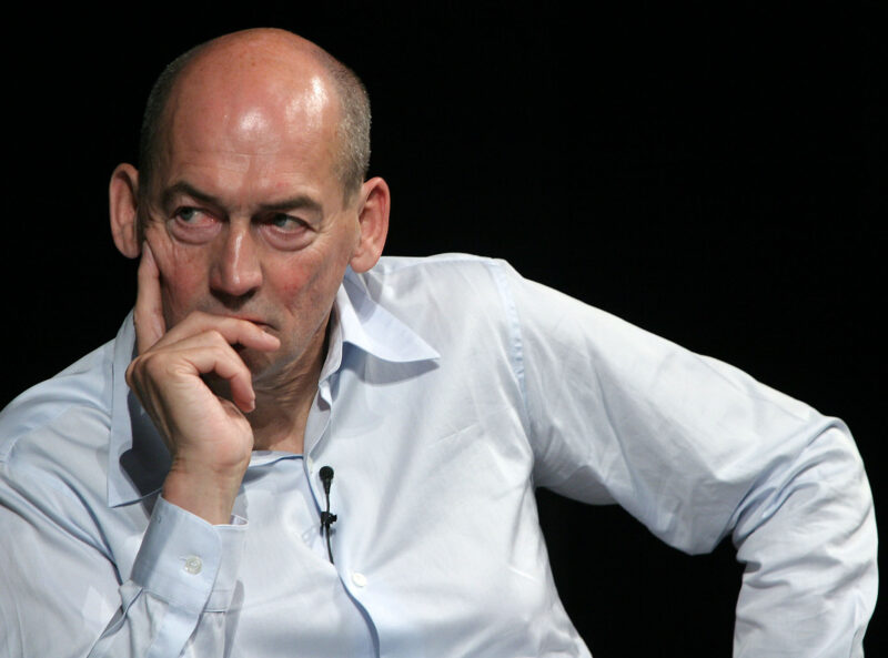 Famous engineers include REm Koolhaas shown in this photo of a bald man wearing a white shirt and a microphone with his head in his hand.