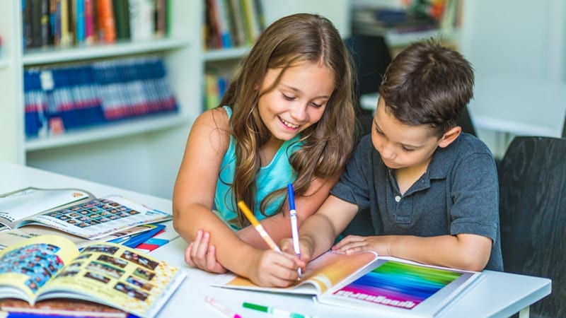 two children creating a yearbook with markers