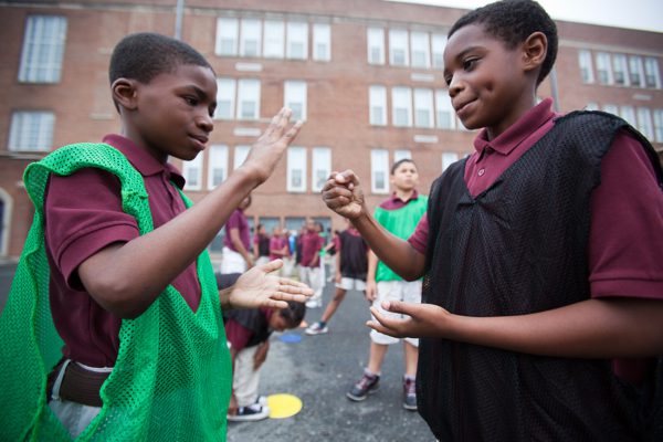 two school children playing rock-paper-scissors on a school playground, as an example of team-building games and activities