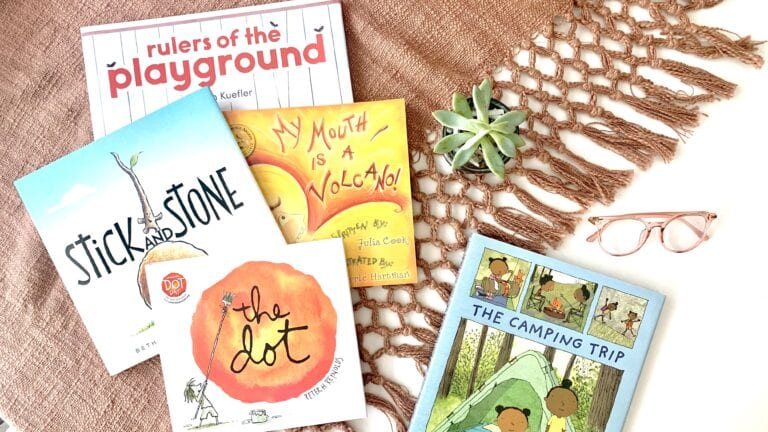 Five social emotional books laid out on a mauve blanket with reading glasses and a succulent.