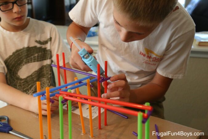 boys building roller coaster from plastic straws 